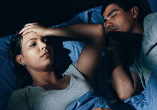 Frau liegt schlaflos im Bett